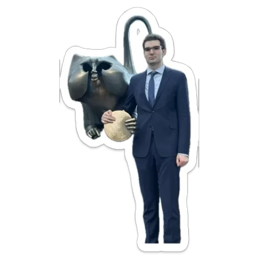 JP in a suit, holding the gold disc of a bronze statue